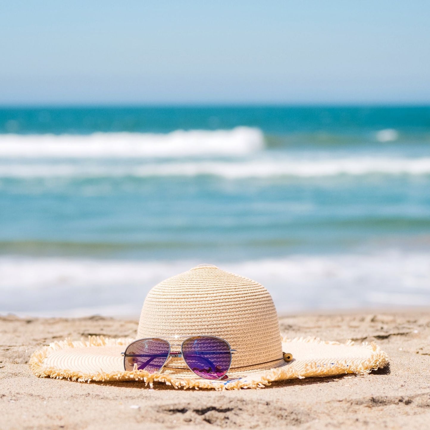 Straw sun hat and sunglasses on the beach